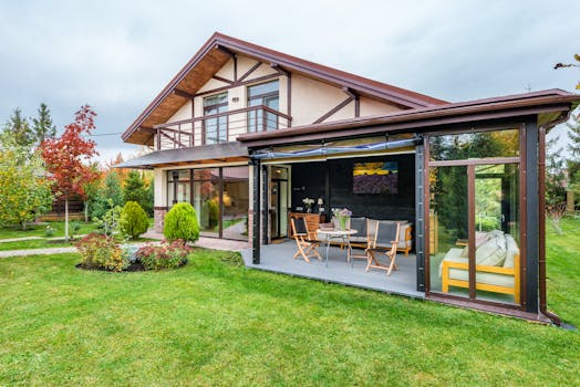 Residential cottage with balcony and opened veranda opening view on lawn and trees growing in backyard